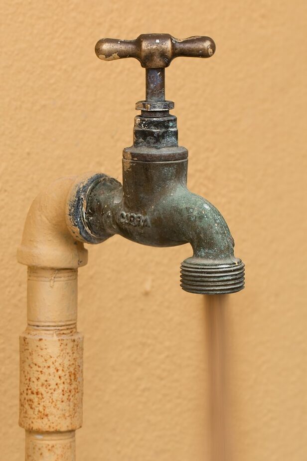 outside spout with brown water flowing out 